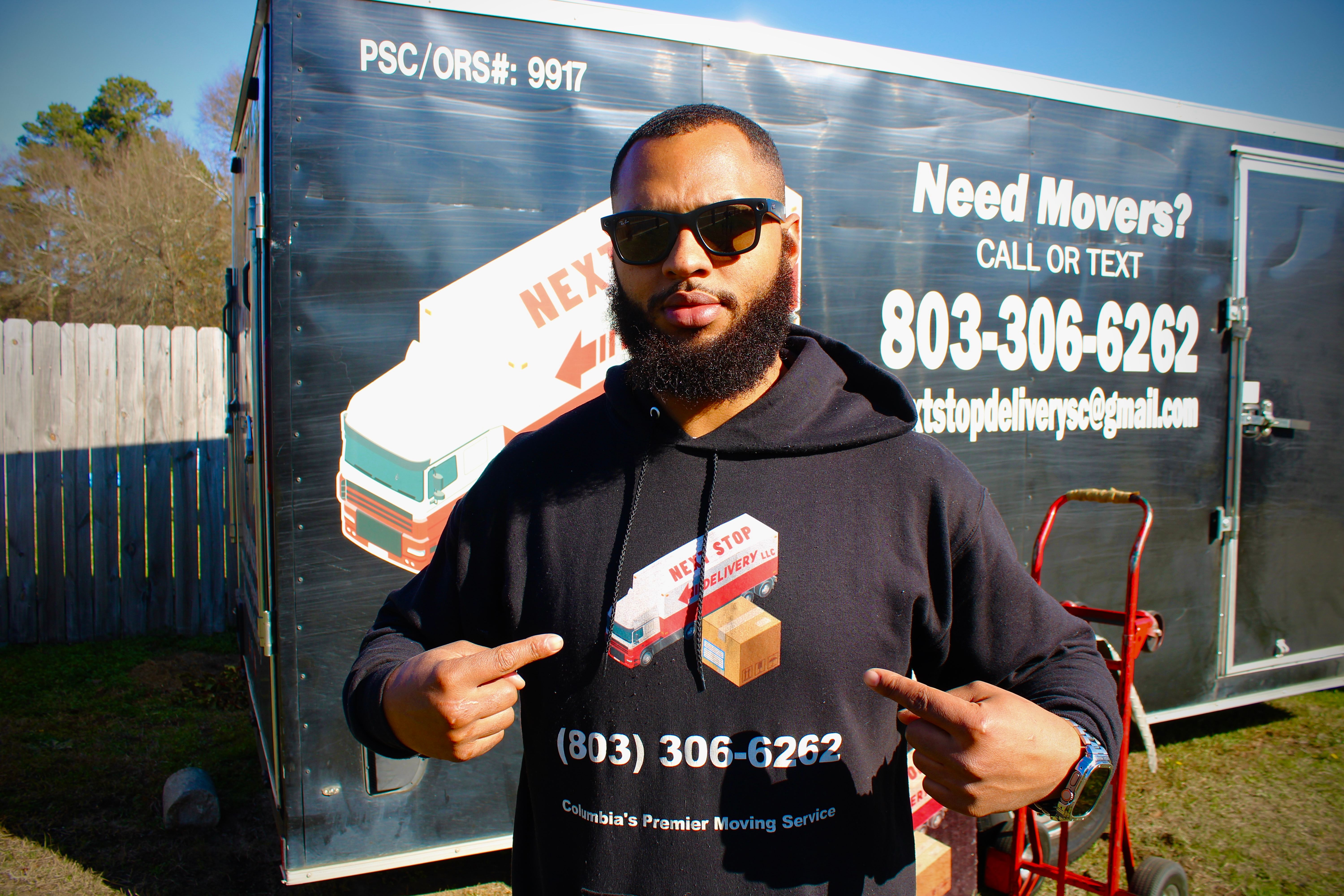Next Stop Delivery team member in a branded hoodie in front of the company moving trailer in Columbia, SC
